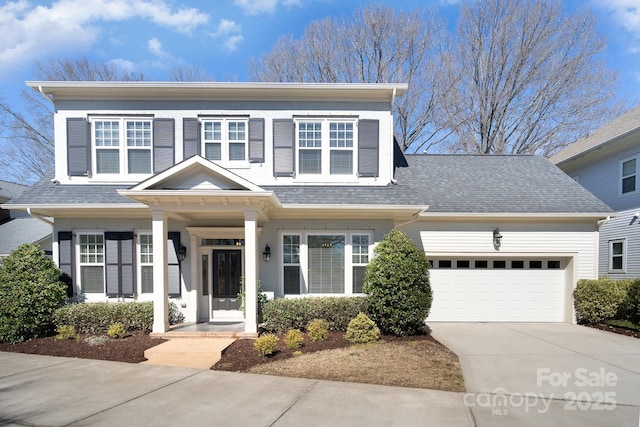 traditional home with an attached garage, a shingled roof, and concrete driveway