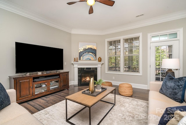 living area with crown molding, visible vents, dark wood finished floors, and a fireplace