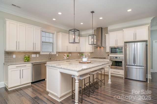 kitchen featuring a kitchen island, a sink, visible vents, appliances with stainless steel finishes, and wall chimney exhaust hood