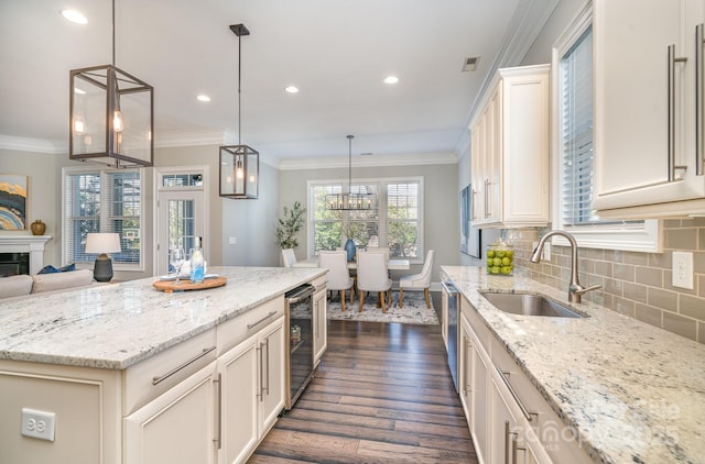 kitchen featuring crown molding, tasteful backsplash, visible vents, a sink, and beverage cooler