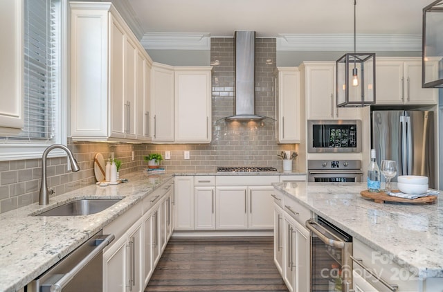 kitchen with stainless steel appliances, tasteful backsplash, ornamental molding, a sink, and wall chimney range hood