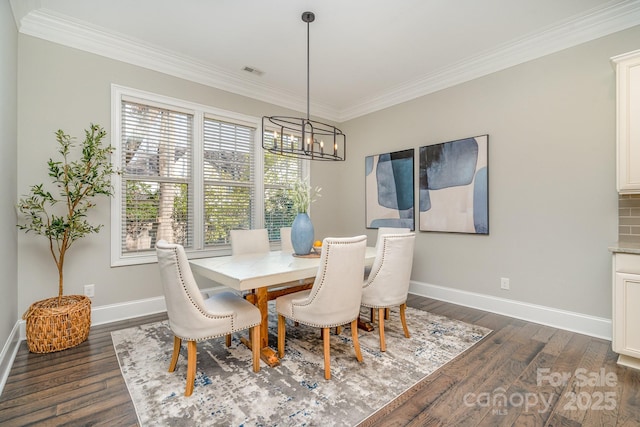 dining room featuring dark wood-style floors, ornamental molding, an inviting chandelier, and baseboards