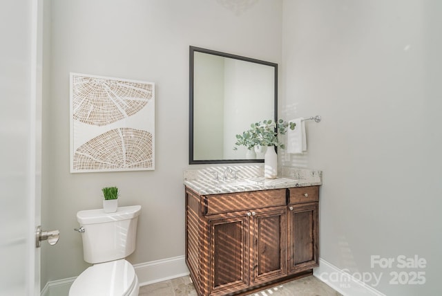 bathroom with toilet, baseboards, and vanity