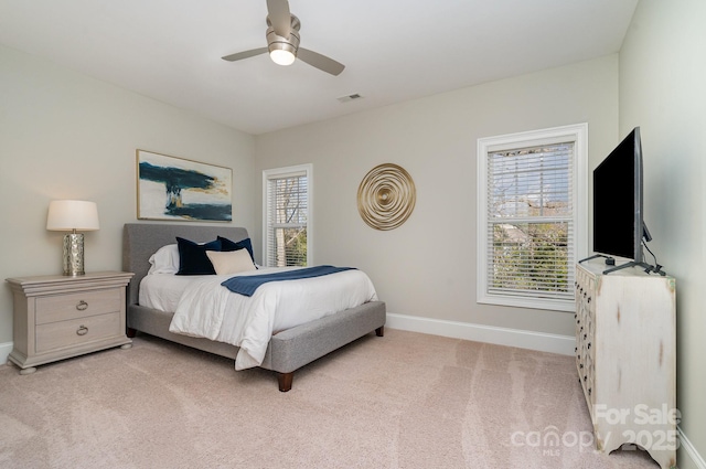 bedroom with light carpet, ceiling fan, visible vents, and baseboards