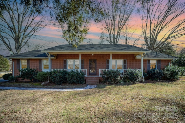 ranch-style home with covered porch and a lawn