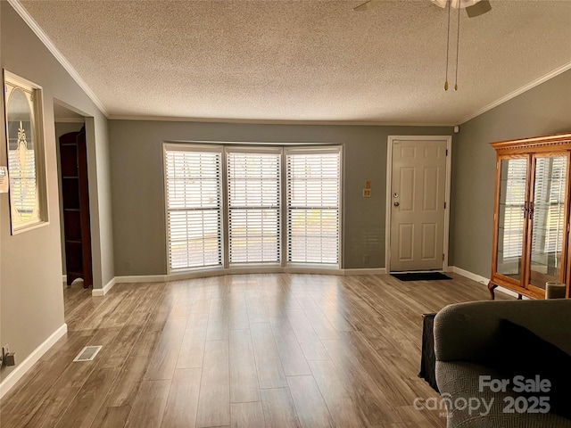 unfurnished living room with a wealth of natural light, ornamental molding, and light wood-type flooring