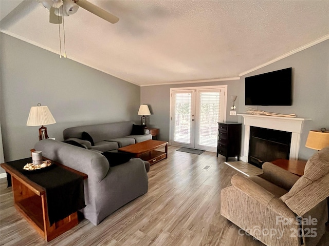 living room featuring ornamental molding, vaulted ceiling, hardwood / wood-style floors, and a textured ceiling