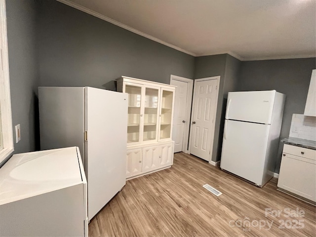 kitchen with light wood-type flooring, white cabinets, and white refrigerator