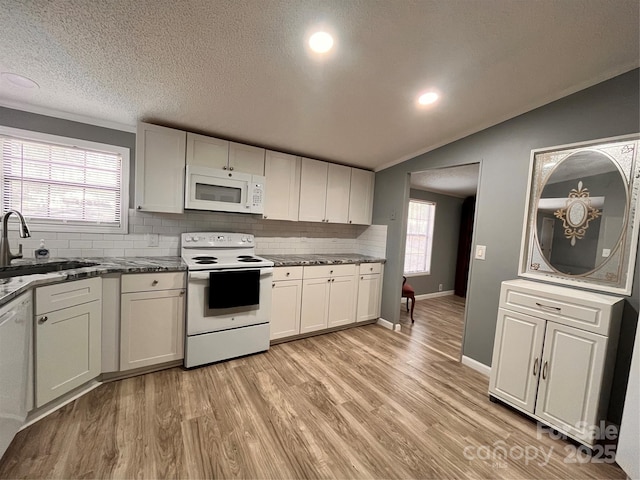 kitchen with vaulted ceiling, white appliances, sink, and light wood-type flooring