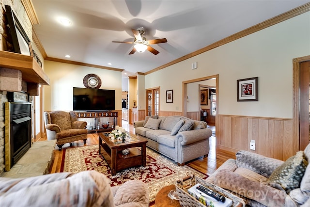 living room with crown molding, a stone fireplace, light hardwood / wood-style flooring, and ceiling fan