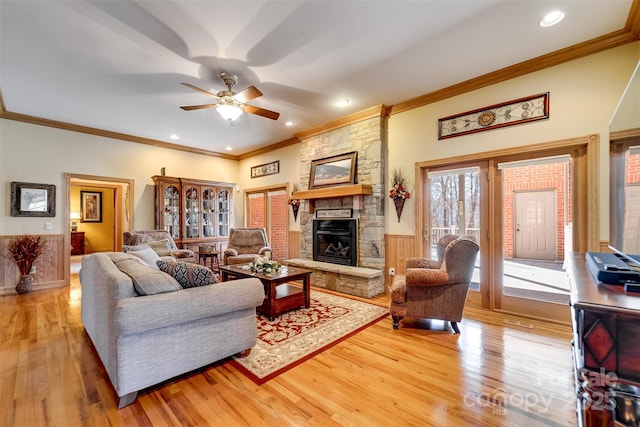 living room featuring crown molding, ceiling fan, a fireplace, and light hardwood / wood-style floors