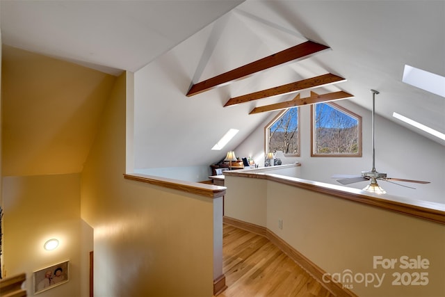 hallway with lofted ceiling with skylight and light wood-type flooring