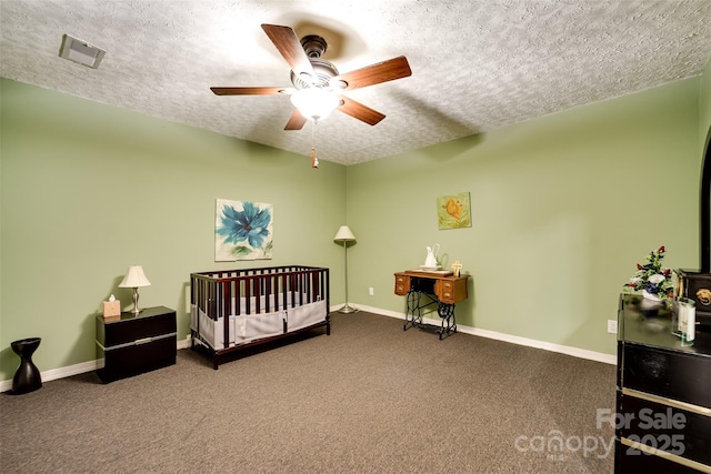 bedroom featuring ceiling fan, a crib, a textured ceiling, and carpet