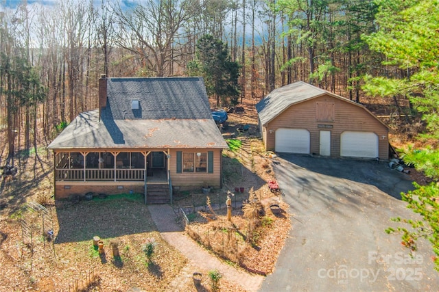 view of front of house featuring a garage, an outdoor structure, and a sunroom