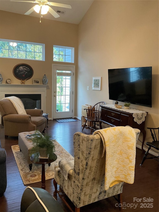 living room with ceiling fan, dark hardwood / wood-style flooring, and high vaulted ceiling