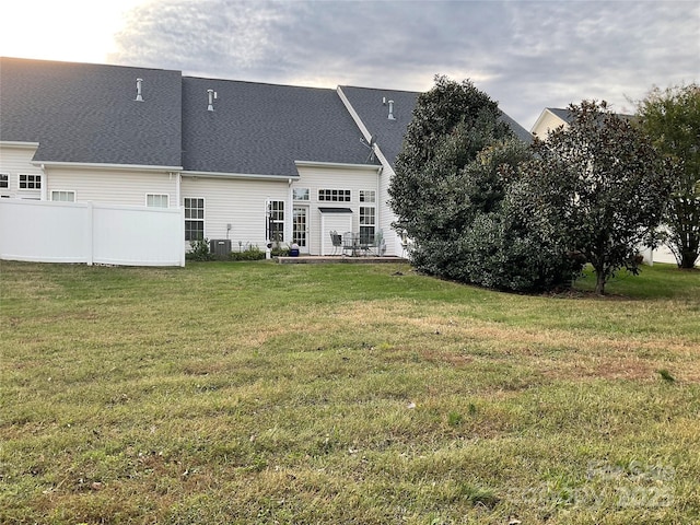 back of house with cooling unit and a lawn