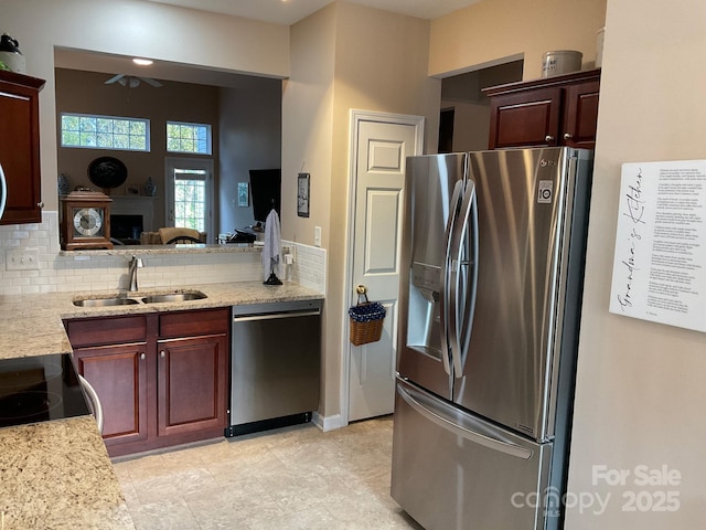 kitchen featuring sink, ceiling fan, appliances with stainless steel finishes, backsplash, and light stone countertops