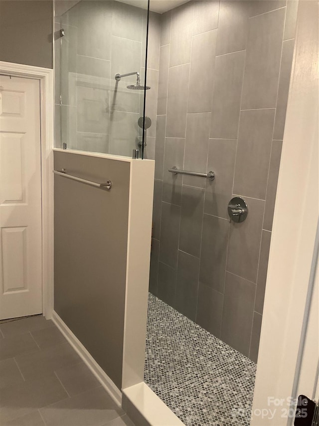 bathroom with tile patterned flooring and a tile shower