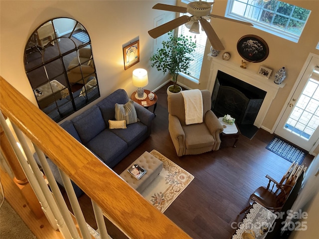 living room featuring dark wood-type flooring, ceiling fan, and a high ceiling