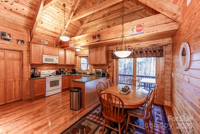 kitchen with white appliances, hanging light fixtures, and wood walls