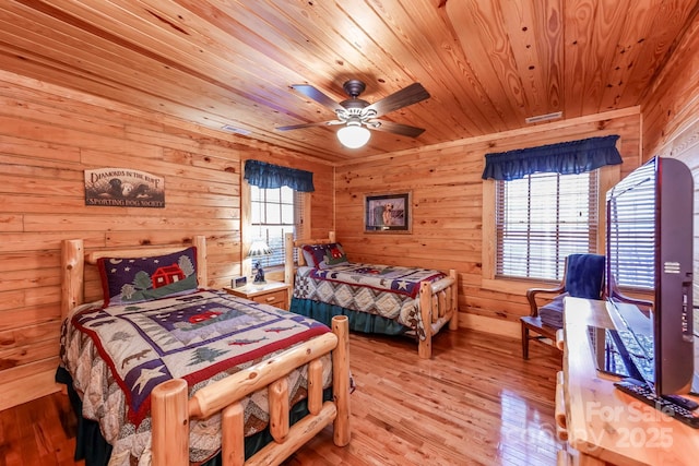 bedroom with ceiling fan, wooden walls, light hardwood / wood-style floors, and wooden ceiling