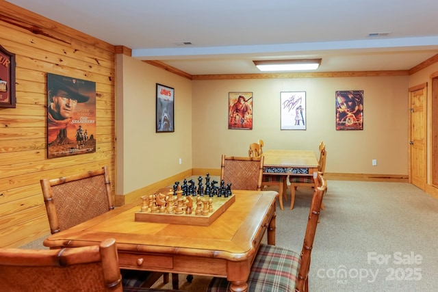 carpeted dining area featuring ornamental molding and wooden walls