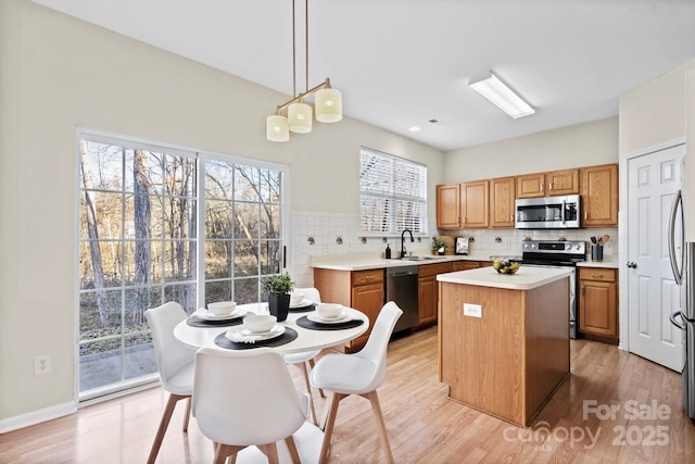 kitchen featuring a kitchen island, appliances with stainless steel finishes, pendant lighting, sink, and light wood-type flooring