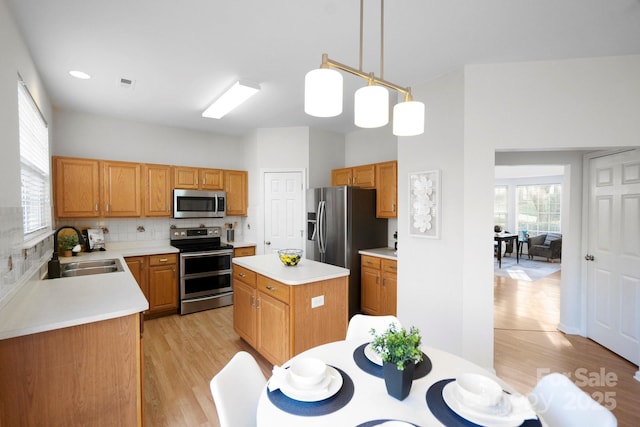 kitchen with sink, appliances with stainless steel finishes, backsplash, hanging light fixtures, and a kitchen island