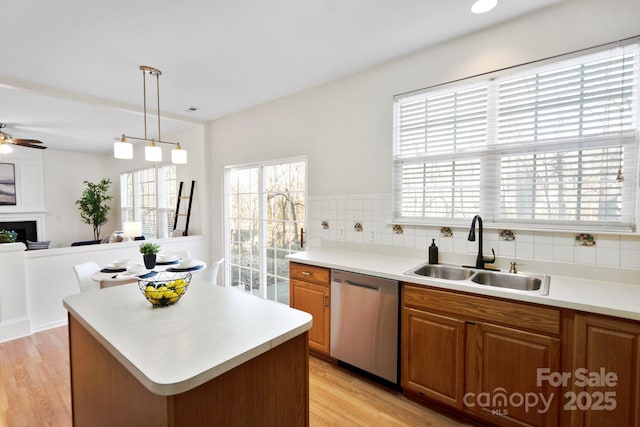 kitchen featuring sink, decorative light fixtures, a center island, light wood-type flooring, and dishwasher