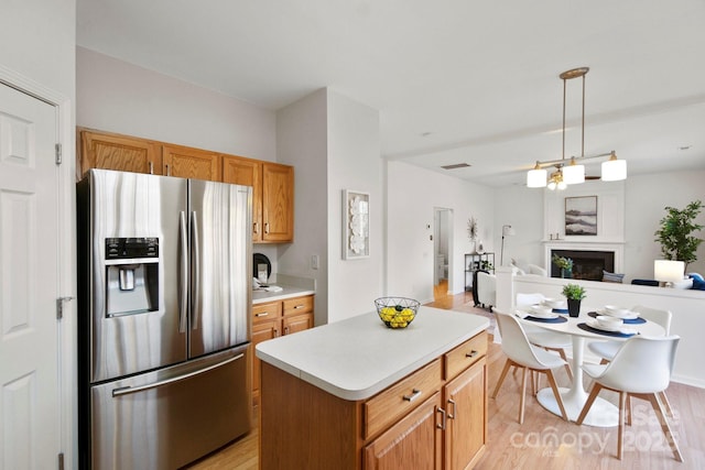 kitchen featuring light hardwood / wood-style flooring, a notable chandelier, a kitchen island, stainless steel fridge with ice dispenser, and decorative light fixtures