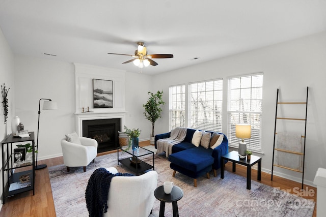 living room featuring hardwood / wood-style flooring, ceiling fan, and a fireplace