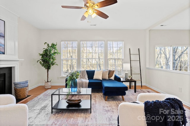 living room with a healthy amount of sunlight, hardwood / wood-style floors, a large fireplace, and ceiling fan