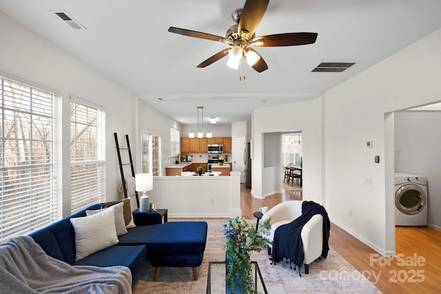 living room featuring ceiling fan, sink, washer / clothes dryer, and light hardwood / wood-style floors