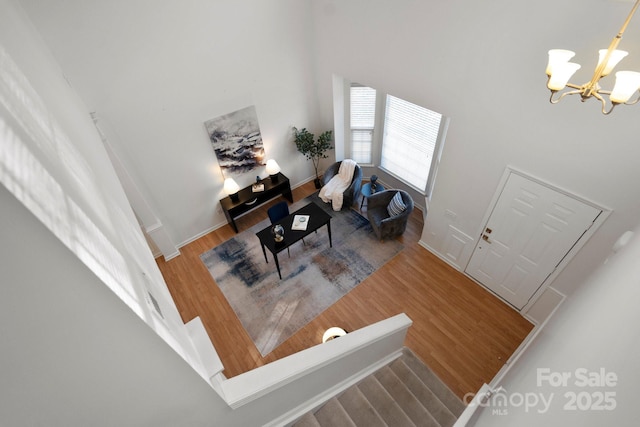 entrance foyer with an inviting chandelier, wood-type flooring, and a high ceiling