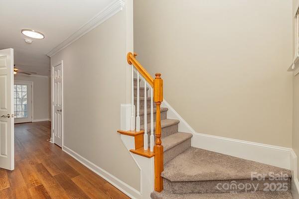 staircase with wood-type flooring and ornamental molding