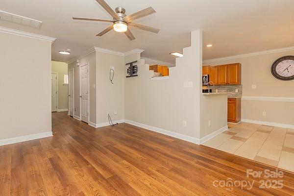 unfurnished living room featuring crown molding, ceiling fan, and light hardwood / wood-style flooring