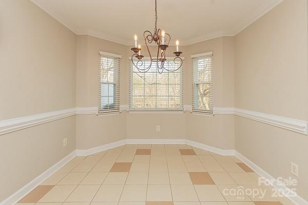 spare room with ornamental molding, plenty of natural light, and a notable chandelier