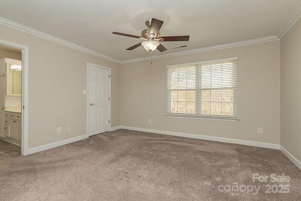 empty room with ornamental molding and light carpet