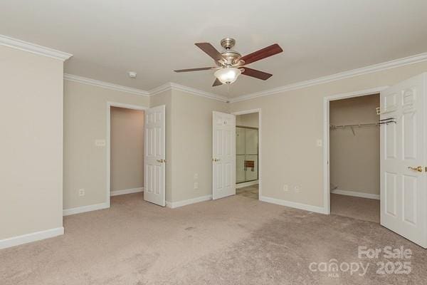 unfurnished bedroom with ceiling fan, ornamental molding, light carpet, a spacious closet, and a closet