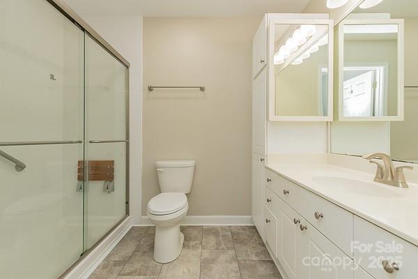 bathroom with toilet, vanity, and a shower with shower door