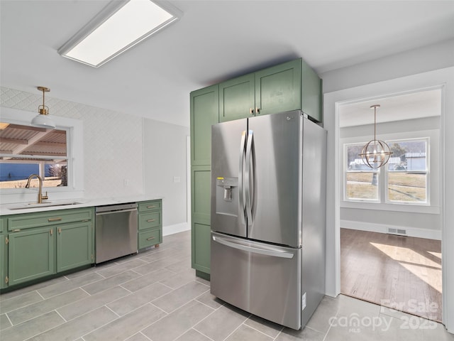 kitchen featuring pendant lighting, sink, green cabinets, a notable chandelier, and stainless steel appliances