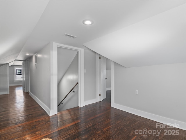 additional living space featuring vaulted ceiling and dark wood-type flooring