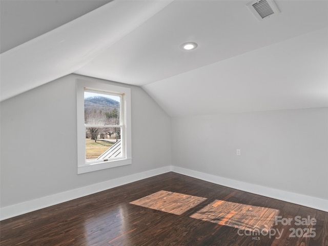 additional living space with dark wood-type flooring and vaulted ceiling