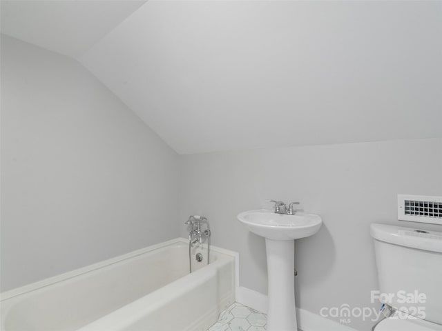 bathroom featuring lofted ceiling, toilet, and a tub