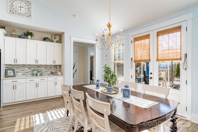 dining area featuring lofted ceiling, a healthy amount of sunlight, light hardwood / wood-style flooring, and french doors