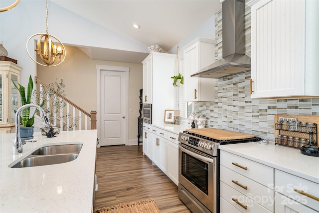 kitchen featuring wall chimney exhaust hood, sink, white cabinetry, appliances with stainless steel finishes, and light stone countertops