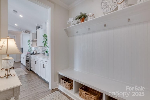 mudroom with crown molding, light hardwood / wood-style flooring, and vaulted ceiling