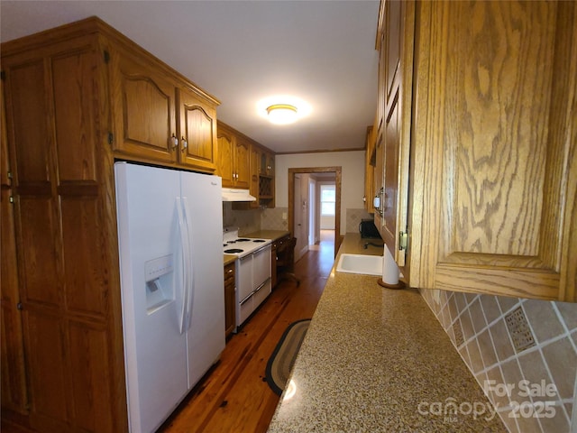 kitchen with tasteful backsplash, light stone countertops, sink, and white appliances