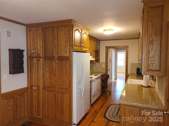 kitchen featuring hardwood / wood-style floors, white appliances, ornamental molding, and decorative backsplash