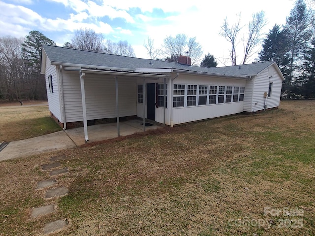 back of property with a yard and a sunroom